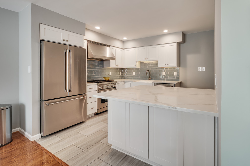 Design ideas for a small modern l-shaped separate kitchen in Philadelphia with a farmhouse sink, recessed-panel cabinets, white cabinets, quartz benchtops, blue splashback, glass tile splashback, stainless steel appliances, vinyl floors, with island, beige floor and white benchtop.