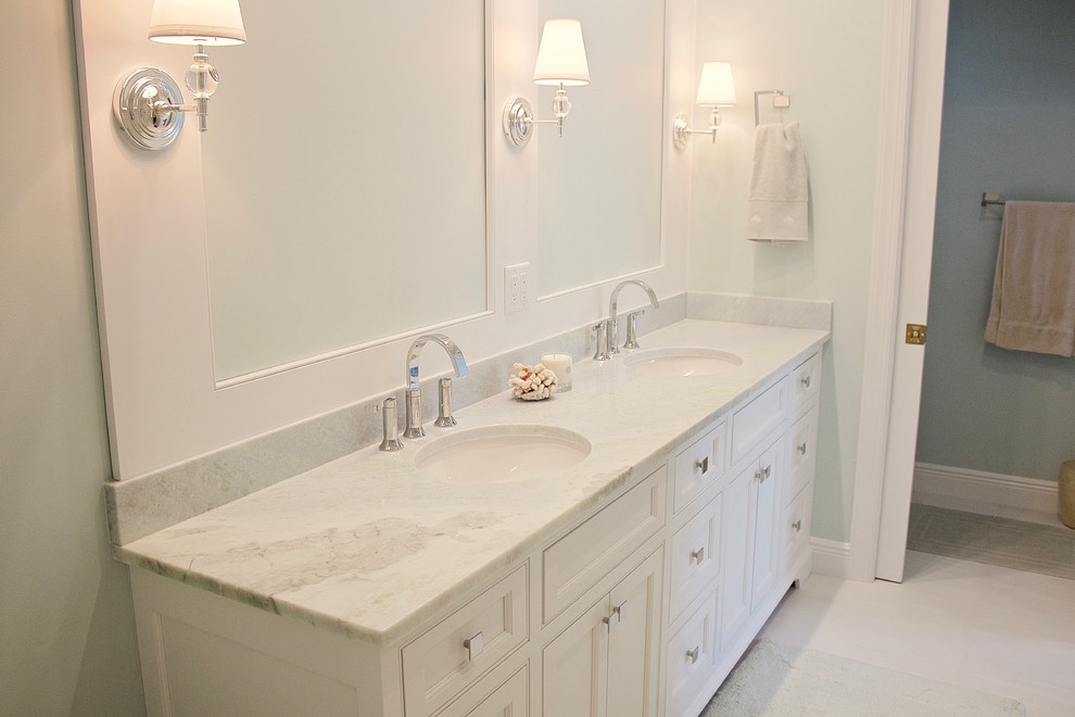 Photo of a mid-sized beach style master bathroom in Miami with shaker cabinets, white cabinets, beige tile, porcelain tile, blue walls, porcelain floors, marble benchtops, an undermount sink and white floor.