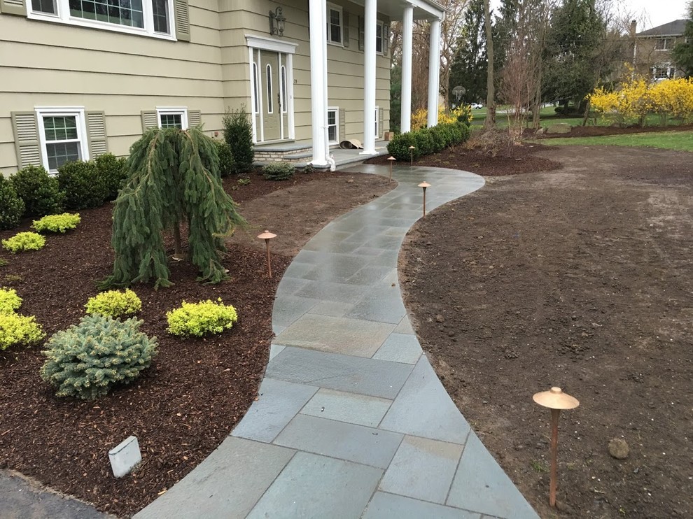 This is an example of a small contemporary front yard shaded garden for fall in New York with a garden path and natural stone pavers.