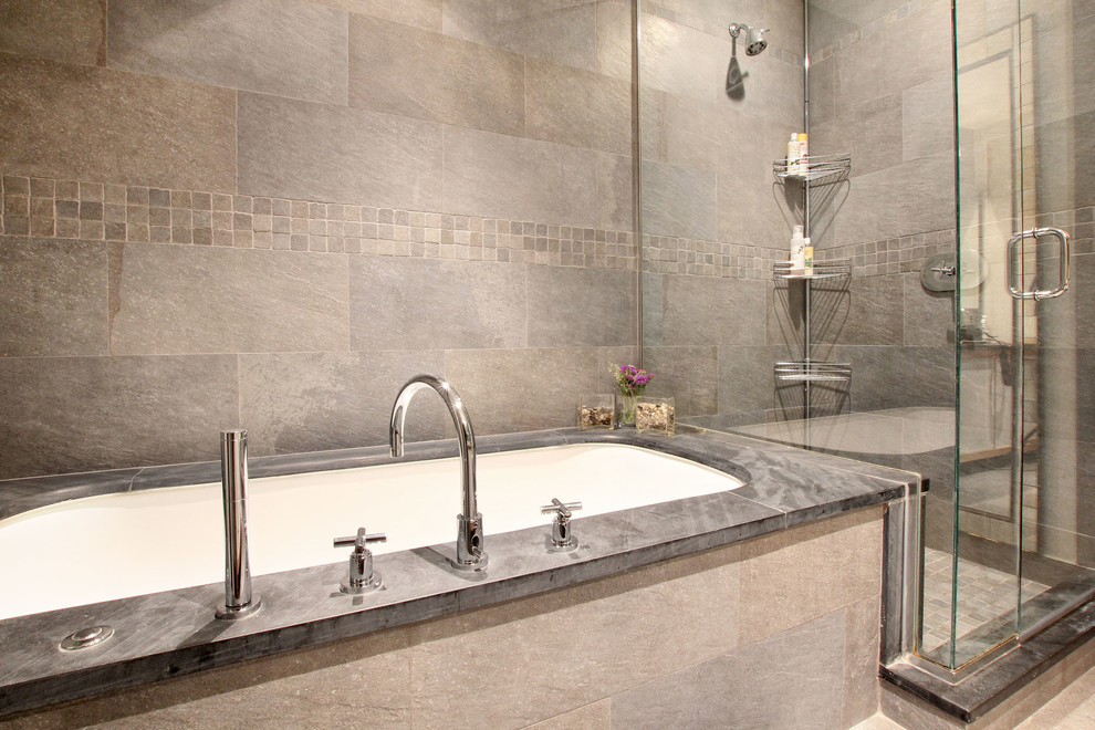 This is an example of a mid-sized contemporary bathroom in New York with an undermount tub, a corner shower, gray tile, stone tile, grey walls and slate floors.