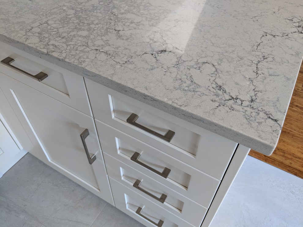 Inspiration for a small transitional u-shaped vinyl floor and beige floor eat-in kitchen remodel in Vancouver with a single-bowl sink, shaker cabinets, white cabinets, quartz countertops, gray backsplash, ceramic backsplash, stainless steel appliances, no island and gray countertops