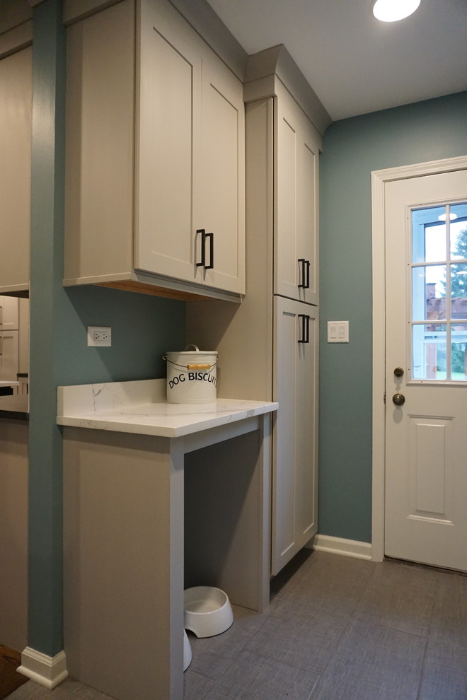 Design ideas for a small transitional galley utility room in Chicago with a single-bowl sink, shaker cabinets, grey cabinets, quartz benchtops, blue walls, porcelain floors, a side-by-side washer and dryer and grey floor.