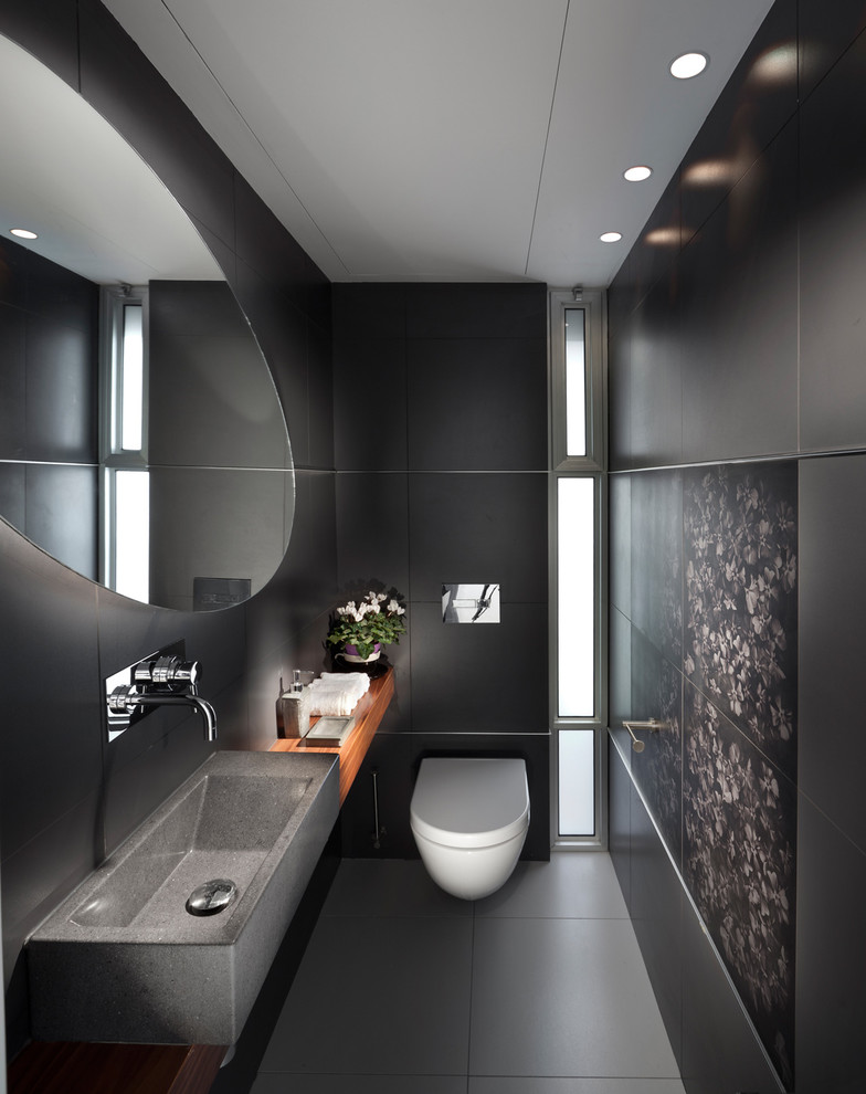 Photo of a contemporary bathroom in Other with a wall-mount toilet, black walls and an integrated sink.