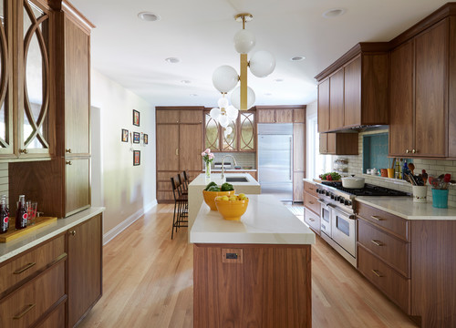 Mid-century modern kitchen with walnut RTA cabinets, white quartz island, brass hardware, globe pendants, blue tile backsplash, pro range, and stainless fridge.