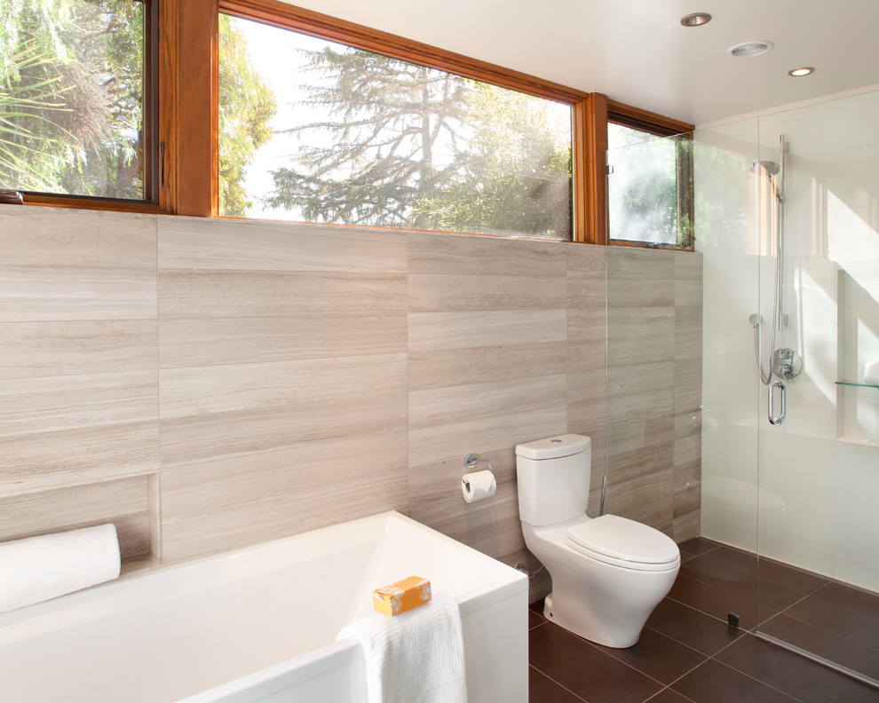 Inspiration for a mid-sized contemporary master bathroom in San Francisco with a curbless shower, a two-piece toilet, gray tile, limestone, flat-panel cabinets, dark wood cabinets, a corner tub, white walls, porcelain floors, a vessel sink, engineered quartz benchtops, brown floor and a hinged shower door.