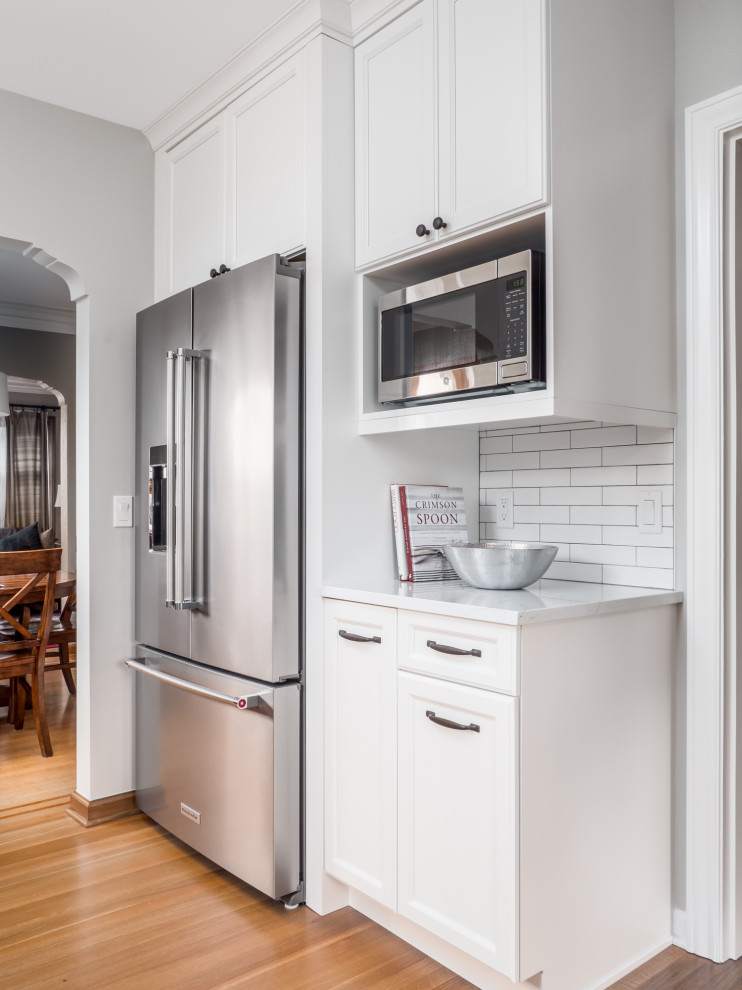 Inspiration for a small transitional galley medium tone wood floor and brown floor enclosed kitchen remodel in Seattle with an undermount sink, recessed-panel cabinets, white cabinets, quartzite countertops, white backsplash, porcelain backsplash, stainless steel appliances, no island and white countertops