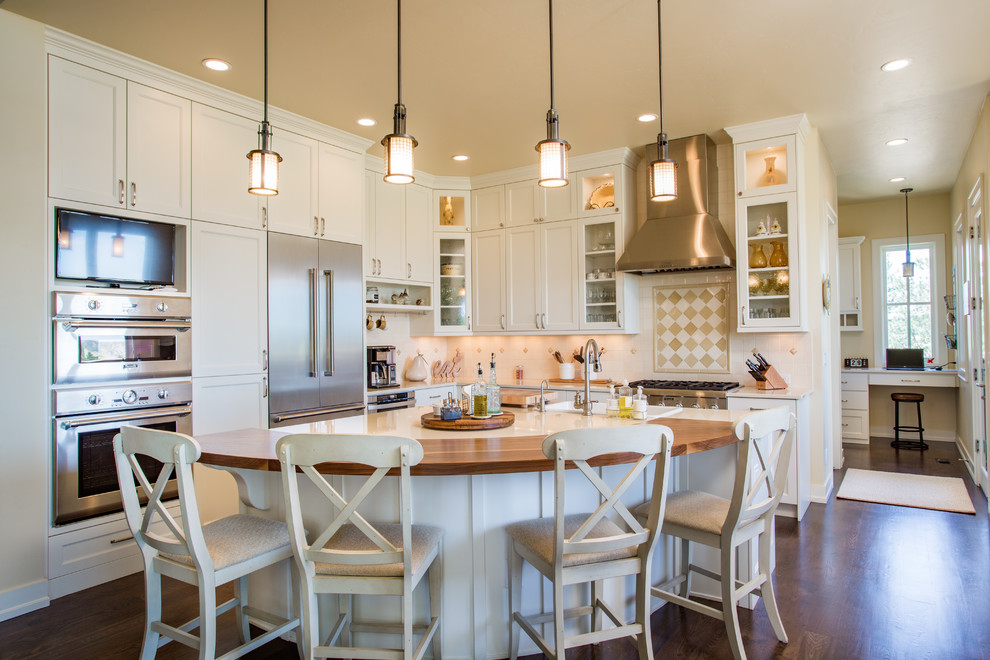 Inspiration for a country l-shaped kitchen in Denver with a drop-in sink, glass-front cabinets, beige cabinets, beige splashback, stainless steel appliances, dark hardwood floors, with island, brown floor and beige benchtop.