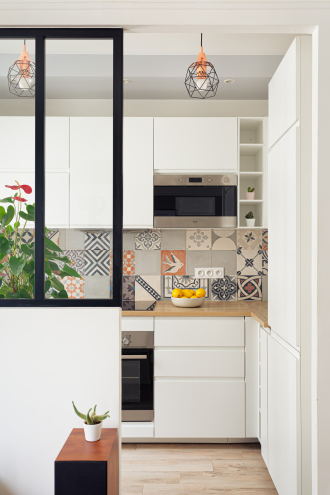 This is an example of a mid-sized modern l-shaped open plan kitchen in Other with an undermount sink, beaded inset cabinets, white cabinets, laminate benchtops, grey splashback, cement tile splashback, stainless steel appliances, ceramic floors, no island, beige floor and beige benchtop.
