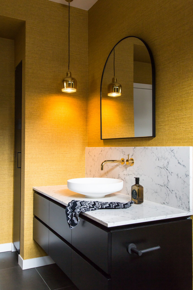 Design ideas for a mid-sized contemporary powder room in Melbourne with furniture-like cabinets, black cabinets, a wall-mount toilet, blue tile, porcelain tile, yellow walls, cement tiles, a vessel sink, engineered quartz benchtops, grey floor, white benchtops, a built-in vanity, recessed and wallpaper.