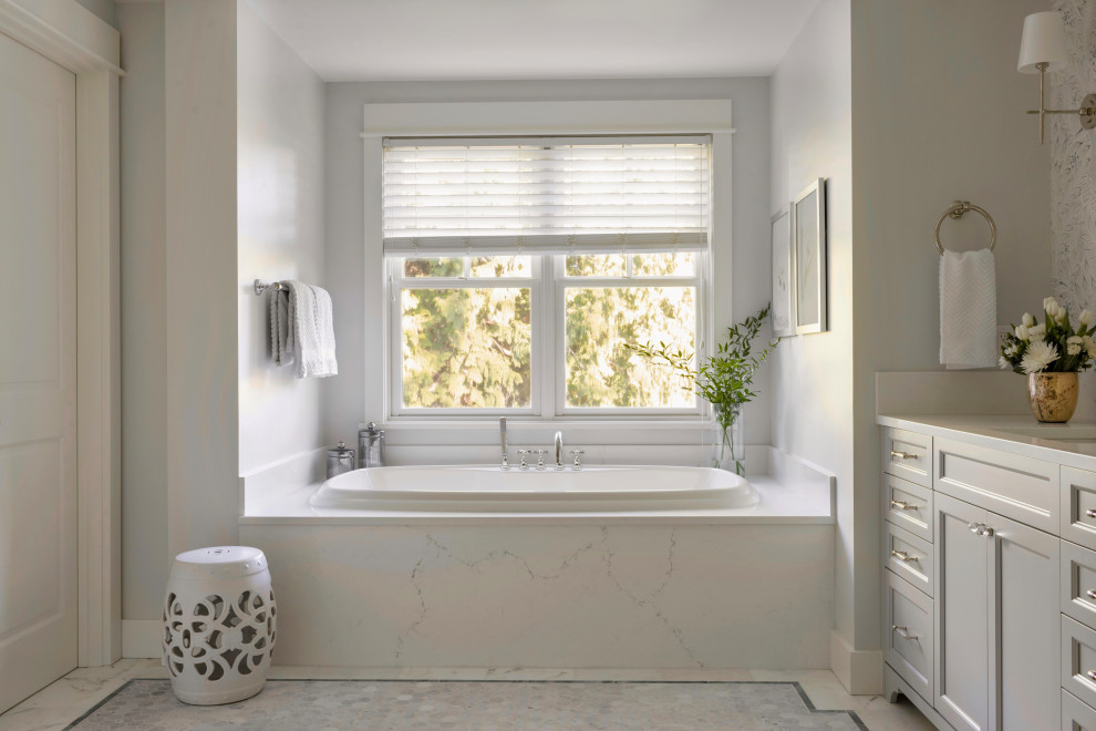 Photo of a large transitional master bathroom in Seattle with recessed-panel cabinets, grey cabinets, a drop-in tub, a double shower, a two-piece toilet, white tile, marble, grey walls, marble floors, an undermount sink, engineered quartz benchtops, white floor, a hinged shower door, white benchtops, a shower seat, a double vanity, a built-in vanity and wallpaper.
