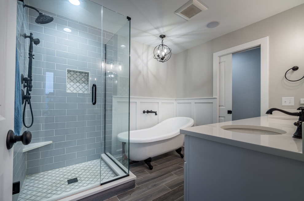Photo of a mid-sized country master bathroom in Chicago with white cabinets, a claw-foot tub, a corner shower, blue tile, ceramic tile, multi-coloured walls, ceramic floors, a drop-in sink, engineered quartz benchtops, grey floor, a hinged shower door, white benchtops, a double vanity, a built-in vanity and decorative wall panelling.