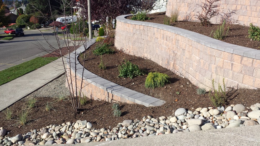 Design ideas for a large eclectic sloped full sun garden in Seattle with a retaining wall.