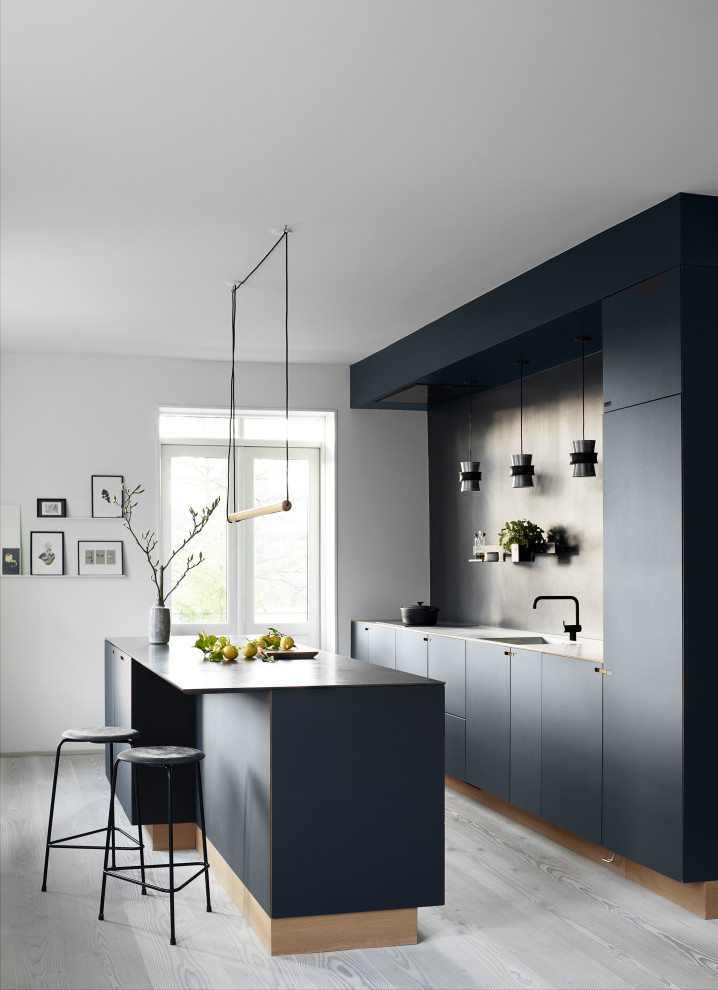 Inspiration for a mid-sized scandinavian galley open plan kitchen in Copenhagen with black cabinets, marble benchtops, with island, flat-panel cabinets, grey splashback, light hardwood floors and grey floor.