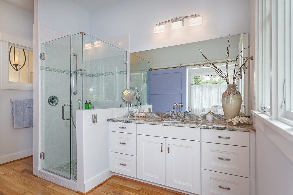 Photo of a mid-sized traditional master bathroom in Raleigh with flat-panel cabinets, white cabinets, a corner shower, a one-piece toilet, glass sheet wall, blue walls, medium hardwood floors, a vessel sink and granite benchtops.