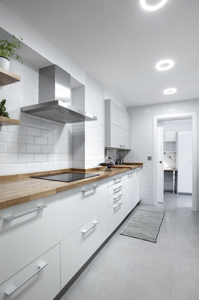 Mid-sized scandinavian single-wall separate kitchen in Other with flat-panel cabinets, white cabinets, wood benchtops, white splashback, subway tile splashback, ceramic floors and no island.
