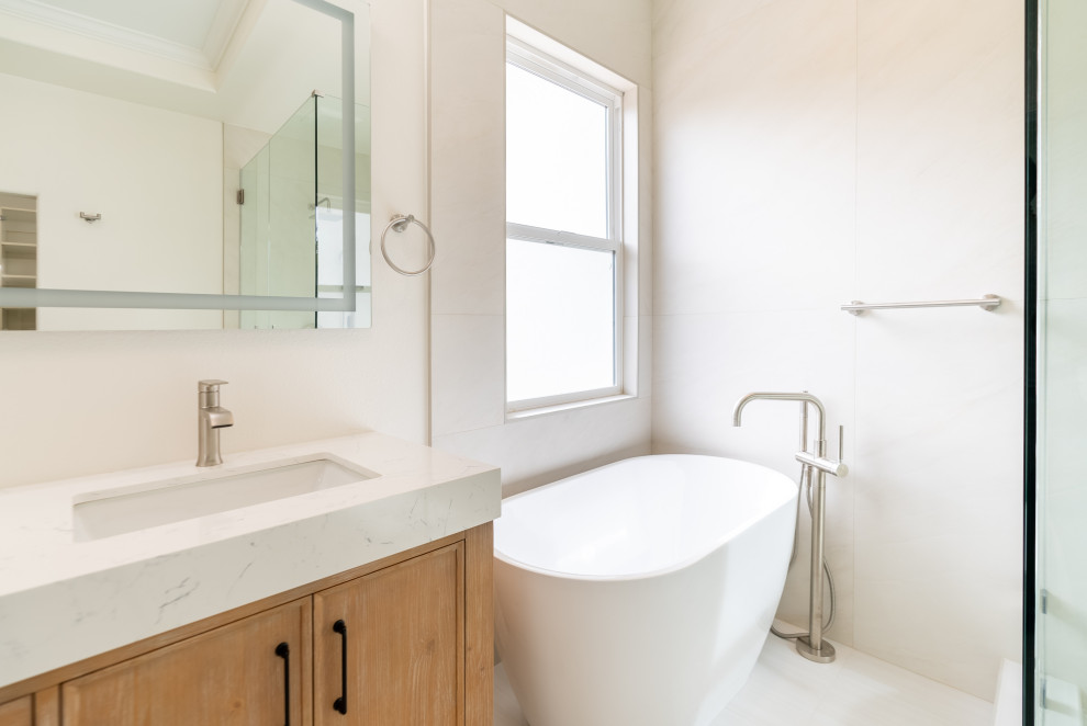Example of a large trendy master white tile and marble tile ceramic tile, beige floor and double-sink bathroom design in Los Angeles with furniture-like cabinets, brown cabinets, a one-piece toilet, white walls, an integrated sink, quartz countertops, a hinged shower door, white countertops and a freestanding vanity
