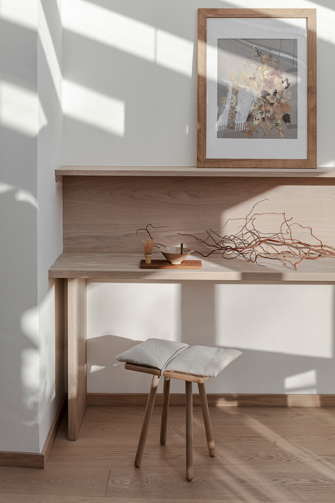 Diseño de despacho asiático de tamaño medio con paredes blancas, suelo de madera clara, escritorio empotrado y suelo marrón