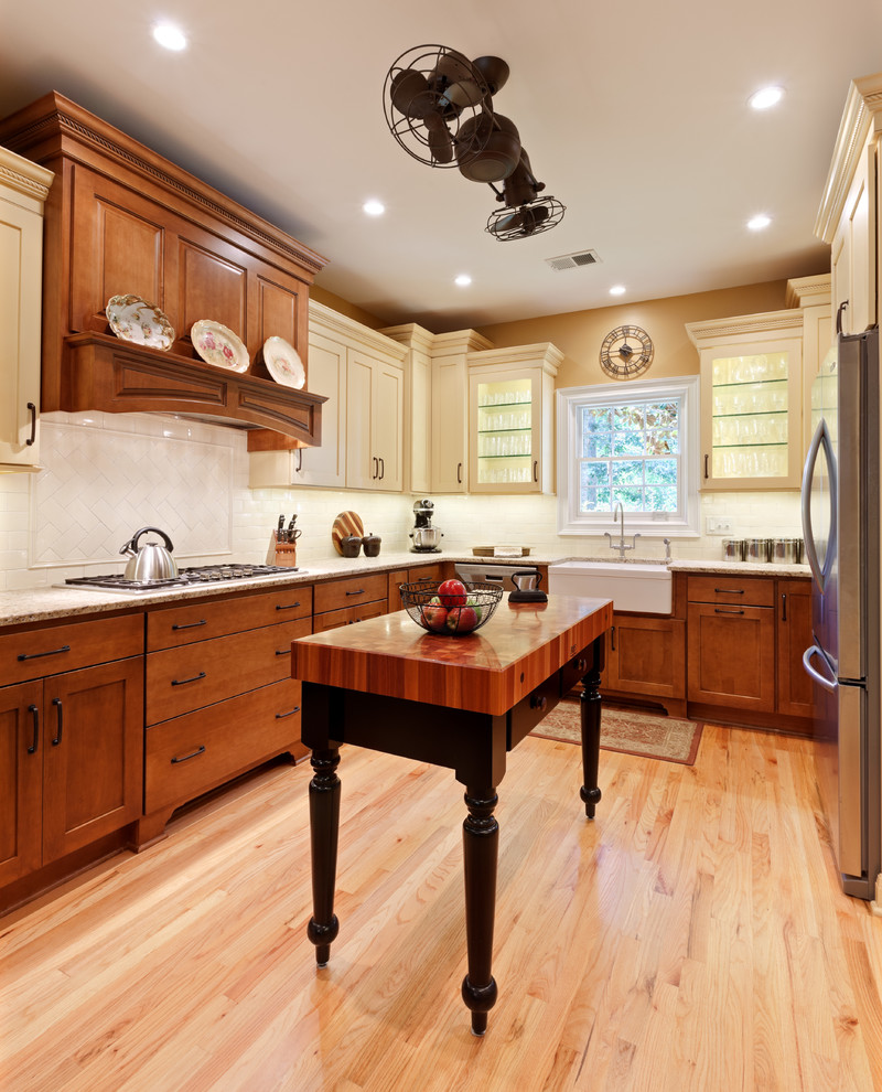 Design ideas for a large traditional u-shaped eat-in kitchen in Atlanta with a farmhouse sink, shaker cabinets, granite benchtops, white splashback, porcelain splashback, stainless steel appliances, light hardwood floors, with island, beige benchtop, medium wood cabinets and brown floor.