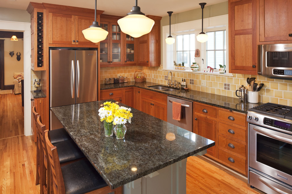 Photo of a traditional l-shaped kitchen in Minneapolis with a double-bowl sink, shaker cabinets, medium wood cabinets, yellow splashback and stainless steel appliances.