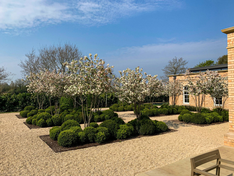 Idee per un grande giardino formale classico esposto in pieno sole dietro casa in primavera con cancello e ghiaia