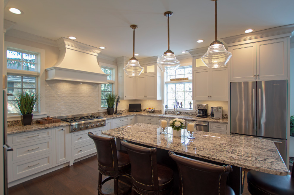 Inspiration for a transitional dark wood floor and brown floor eat-in kitchen remodel with an undermount sink, shaker cabinets, white cabinets, granite countertops, white backsplash, ceramic backsplash, stainless steel appliances, an island and beige countertops