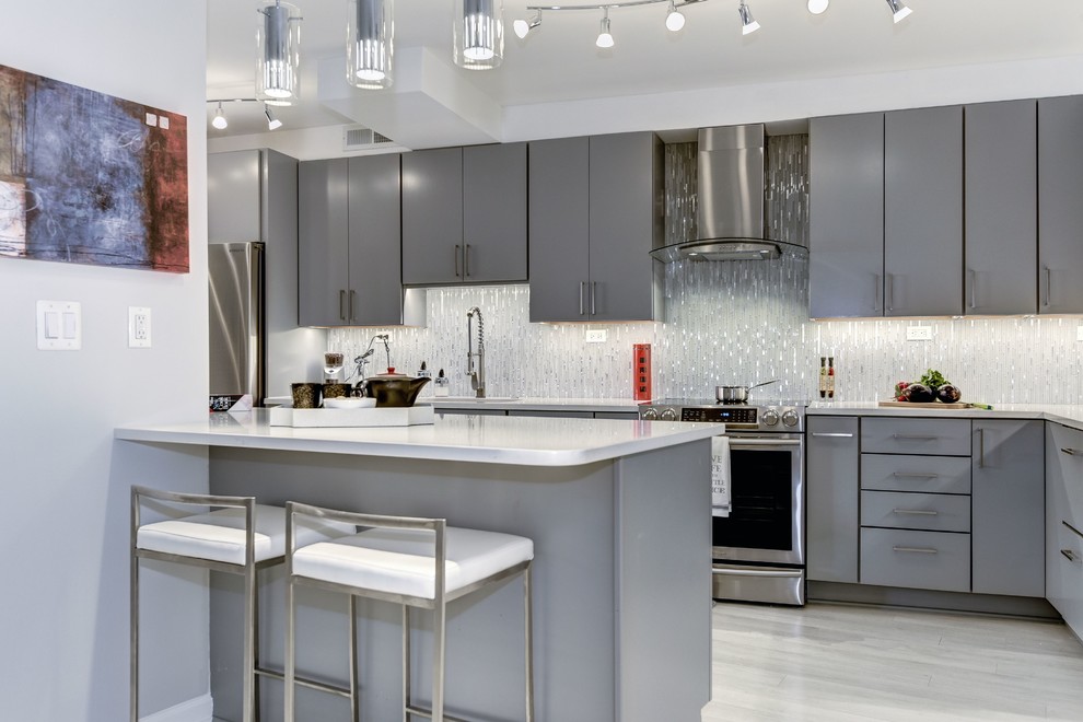 Design ideas for a mid-sized contemporary l-shaped eat-in kitchen in DC Metro with a single-bowl sink, flat-panel cabinets, grey cabinets, quartz benchtops, yellow splashback, glass tile splashback, stainless steel appliances, laminate floors, with island and white floor.