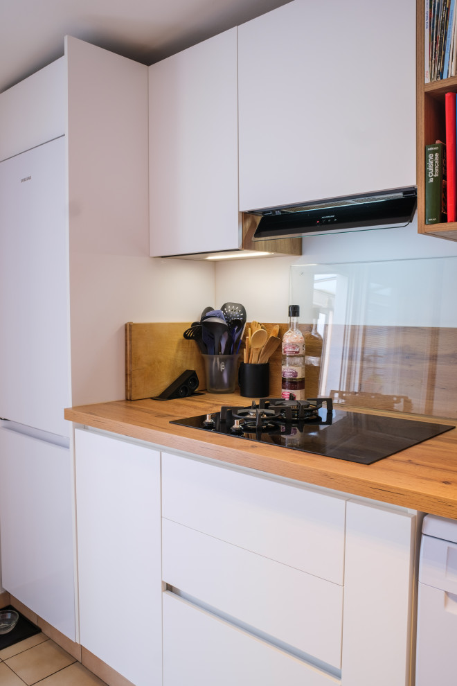Modern l-shaped open plan kitchen in Paris with an integrated sink, wood worktops, beige splashback, wood splashback, black appliances and beige worktops.