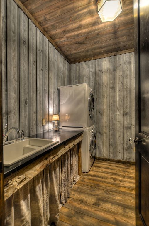 Laundry room - huge rustic medium tone wood floor laundry room idea in Minneapolis with a drop-in sink, gray walls and a stacked washer/dryer