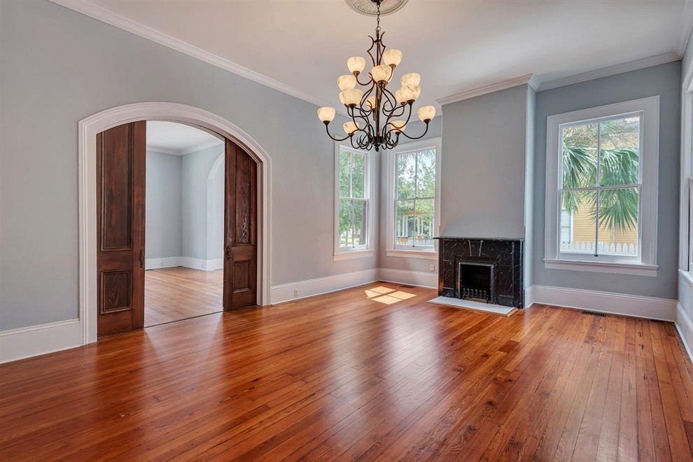 Inspiration for a large timeless medium tone wood floor enclosed dining room remodel in Miami with gray walls, a standard fireplace and a stone fireplace