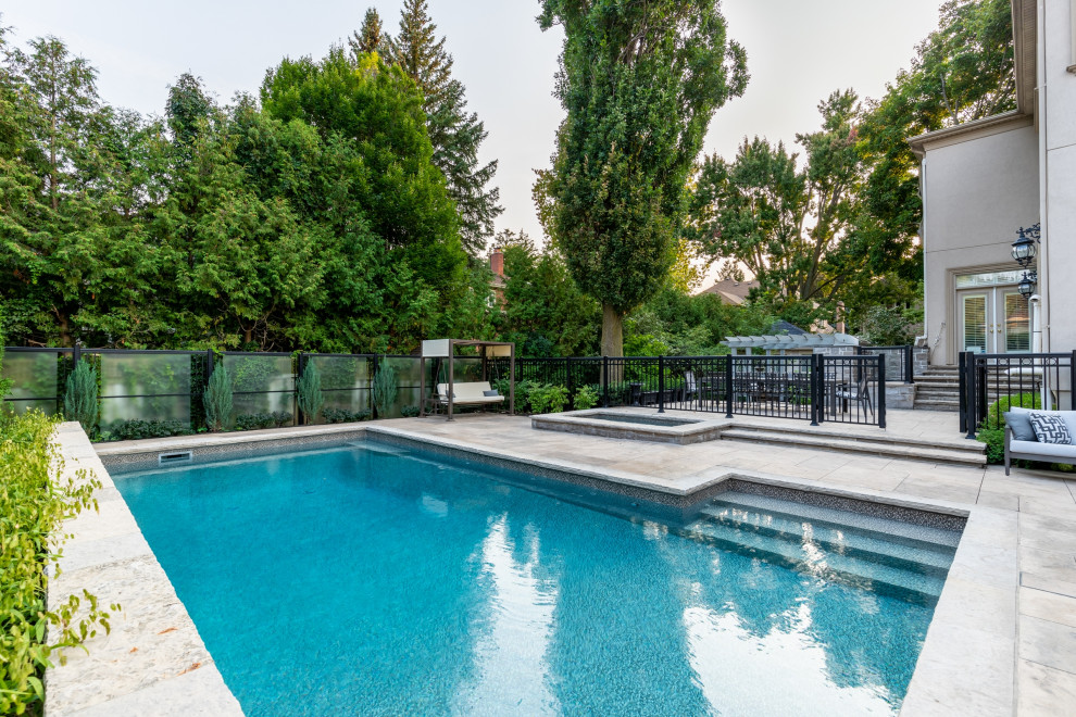 Mid-sized transitional backyard stamped concrete and rectangular pool landscaping photo in Toronto