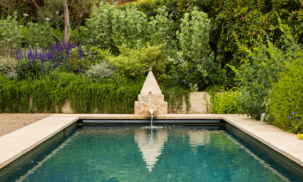 Diseño de piscina mediterránea de tamaño medio rectangular en patio trasero con paisajismo de piscina y adoquines de piedra natural