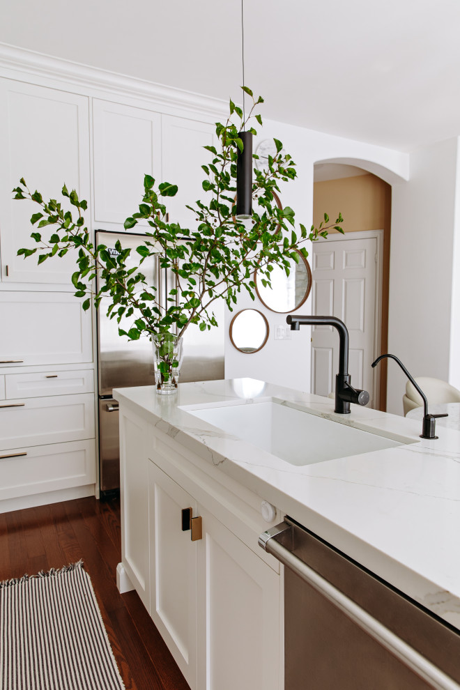 Eat-in kitchen - mid-sized transitional l-shaped dark wood floor and brown floor eat-in kitchen idea in Toronto with an undermount sink, shaker cabinets, white cabinets, quartz countertops, white backsplash, quartz backsplash, black appliances, an island and white countertops