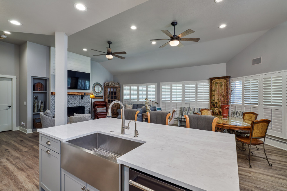 Example of a mid-sized transitional u-shaped vinyl floor and brown floor kitchen pantry design in Austin with a farmhouse sink, shaker cabinets, white cabinets, quartz countertops, white backsplash, marble backsplash, black appliances, two islands and white countertops