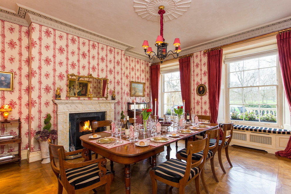 Photo of a mid-sized traditional separate dining room in London with red walls, light hardwood floors, brown floor and a standard fireplace.