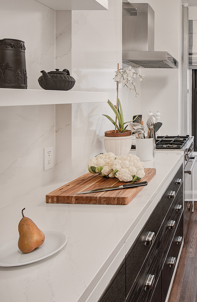 Bild på ett litet funkis vit vitt kök, med en enkel diskho, släta luckor, vita skåp, vitt stänkskydd, stänkskydd i keramik, integrerade vitvaror, mörkt trägolv och brunt golv