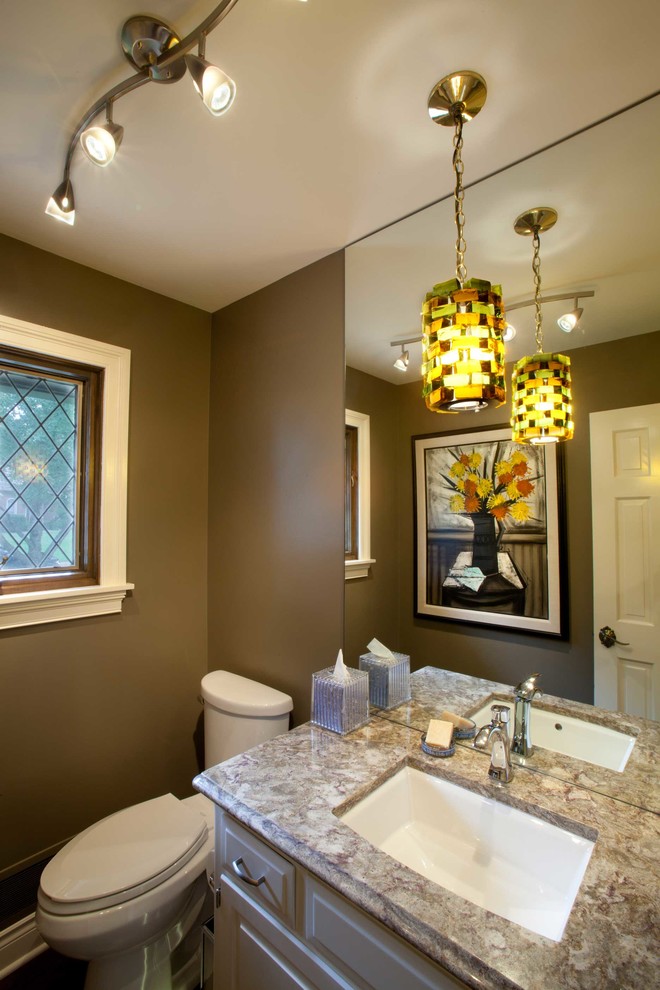 Photo of a small traditional powder room in Kansas City with raised-panel cabinets, dark hardwood floors, an undermount sink, engineered quartz benchtops, white cabinets, a two-piece toilet, brown walls and brown floor.