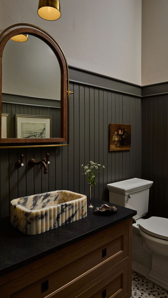 Powder room - country mosaic tile floor, multicolored floor and wainscoting powder room idea in Oklahoma City with recessed-panel cabinets, medium tone wood cabinets, white walls, a vessel sink and black countertops
