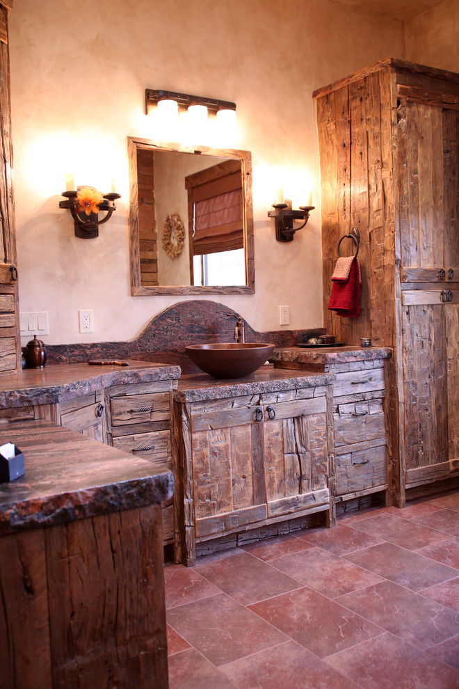 Inspiration for a large country master bathroom in Albuquerque with a vessel sink, flat-panel cabinets, distressed cabinets, granite benchtops, a freestanding tub, red tile, stone tile, beige walls and slate floors.