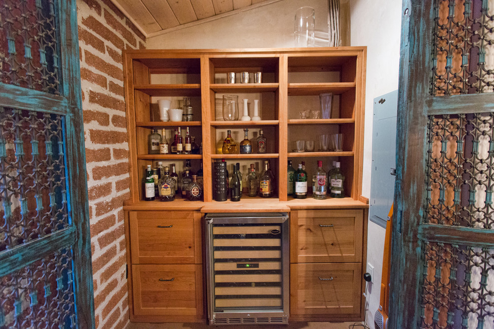 This is an example of a small single-wall wet bar in Phoenix with open cabinets, light wood cabinets, wood benchtops and concrete floors.