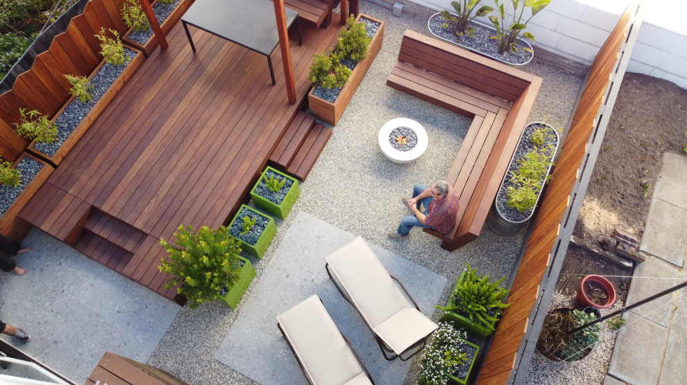 Cette image montre un petit jardin arrière design avec une exposition partiellement ombragée, une terrasse en bois et une clôture en bois.