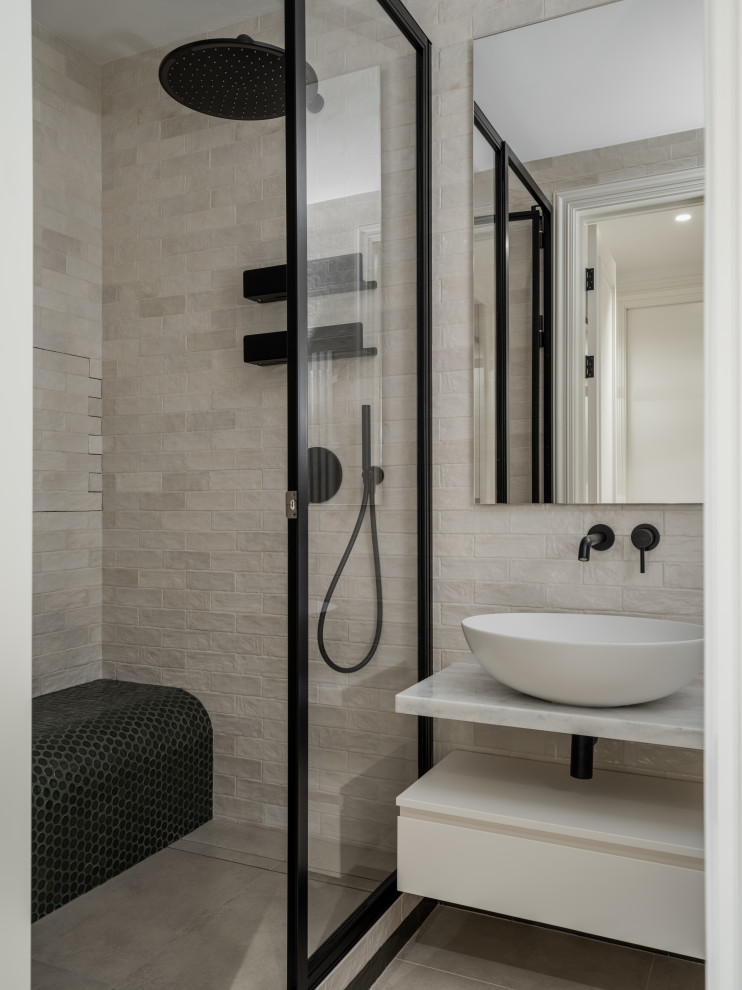 Cette image montre une salle de bain design avec des portes de placard beiges, un mur beige, une vasque, un plan de toilette en marbre, une cabine de douche à porte battante, un plan de toilette blanc, meuble-lavabo suspendu et un banc de douche.
