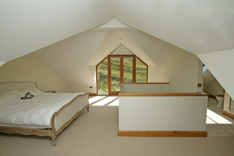 Photo of a country loft-style bedroom in Dorset with white walls and carpet.