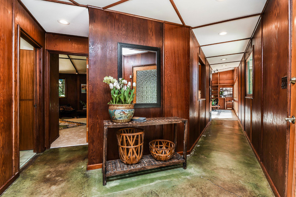 Photo of a large midcentury hallway in San Francisco with brown walls, concrete floors and green floor.