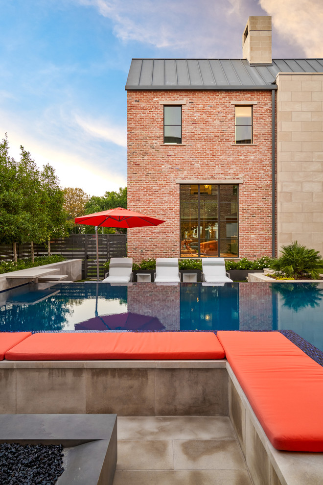 Inspiration for a mid-sized transitional backyard l-shaped infinity pool in Dallas with concrete slab.