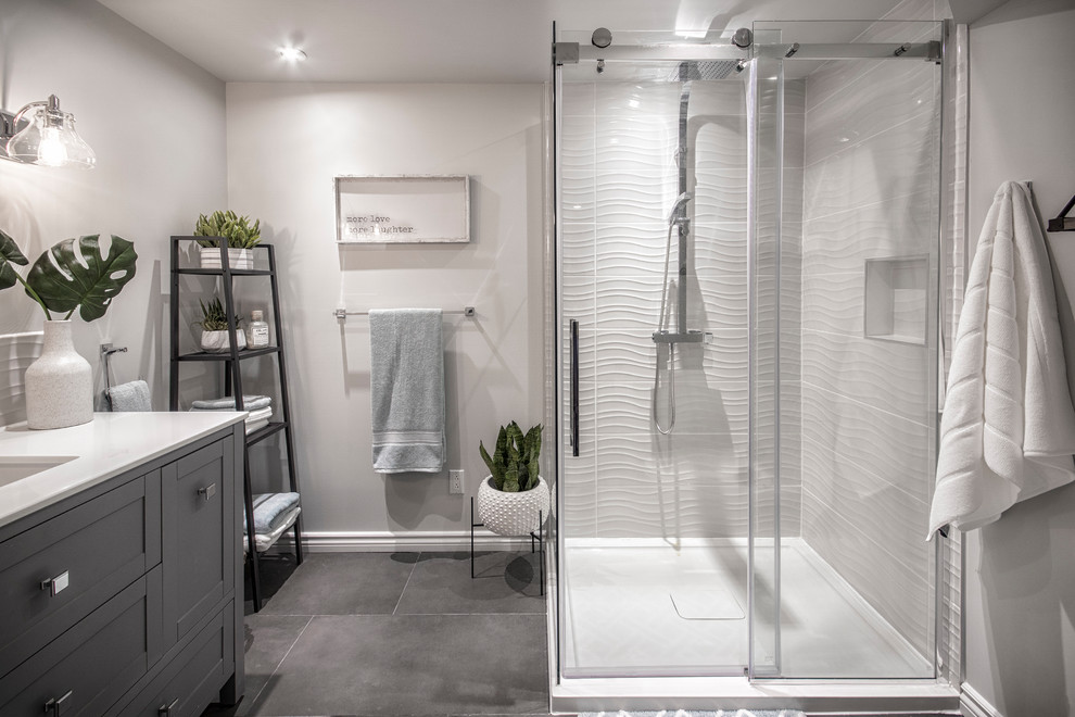 Photo of a mid-sized modern master bathroom in Montreal with shaker cabinets, grey cabinets, an open shower, a one-piece toilet, gray tile, porcelain tile, grey walls, porcelain floors, a drop-in sink, engineered quartz benchtops, grey floor, a sliding shower screen, white benchtops, a single vanity and a built-in vanity.