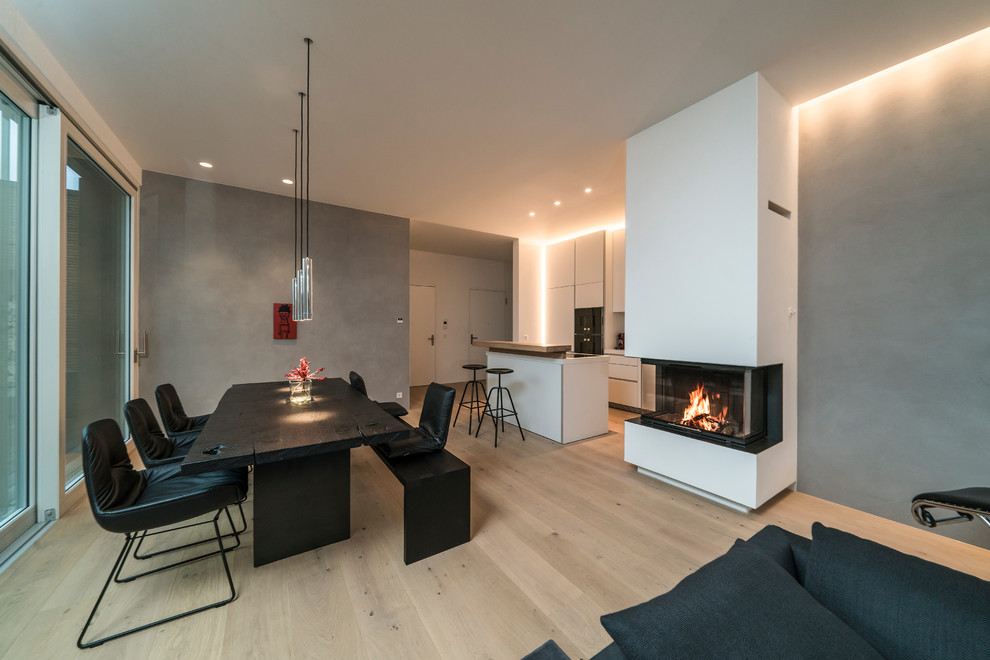 Photo of a large contemporary formal open concept living room in Stuttgart with grey walls, medium hardwood floors, a standard fireplace, a plaster fireplace surround, brown floor and no tv.
