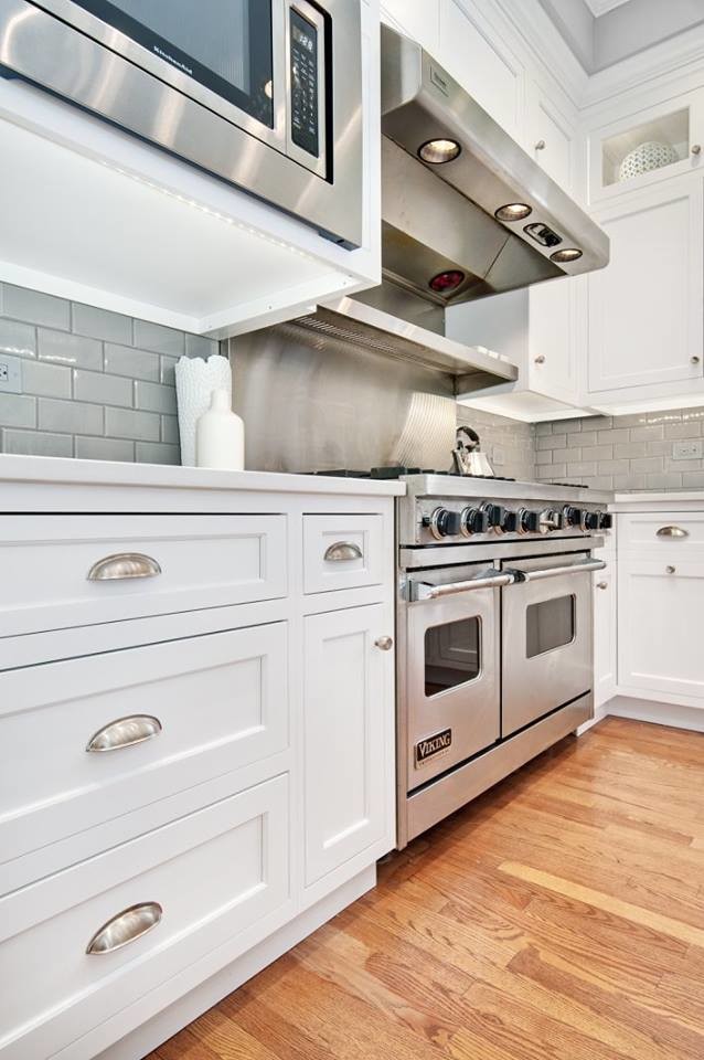Mid-sized transitional l-shaped light wood floor and beige floor kitchen photo in Chicago with an undermount sink, shaker cabinets, white cabinets, quartzite countertops, gray backsplash, subway tile backsplash, stainless steel appliances and an island