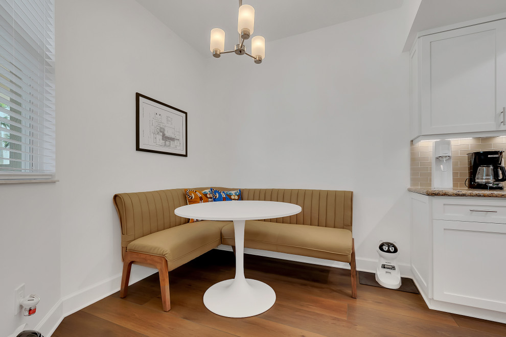 Inspiration pour une salle à manger minimaliste de taille moyenne avec une banquette d'angle, un mur blanc, un sol en vinyl, aucune cheminée, un sol marron et un plafond voûté.