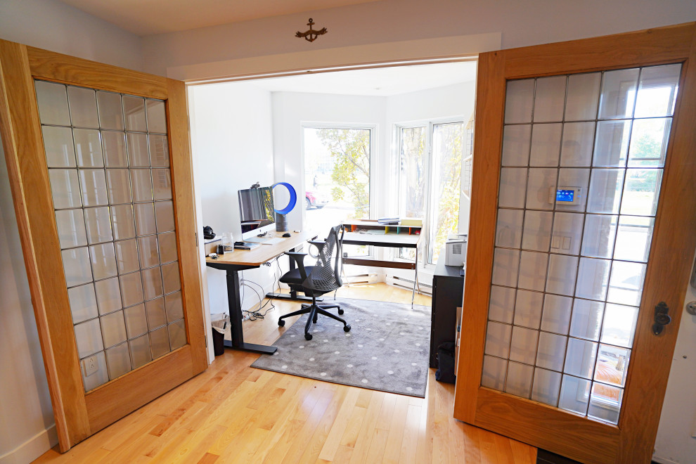 Imagen de estudio blanco tradicional de tamaño medio con suelo de madera clara, escritorio independiente y paredes blancas