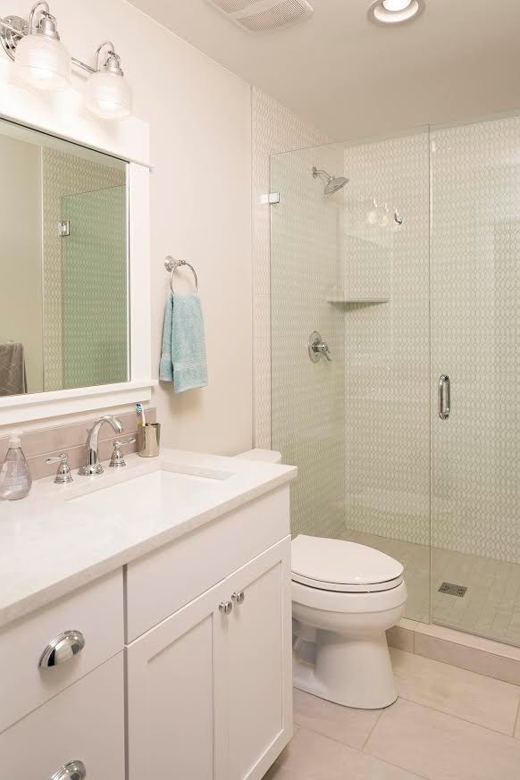 Photo of a mid-sized country 3/4 bathroom in Seattle with shaker cabinets, white cabinets, an alcove shower, a two-piece toilet, white tile, ceramic tile, white walls, porcelain floors, an undermount sink, solid surface benchtops, white floor and a hinged shower door.